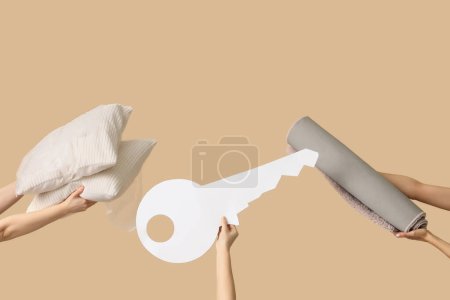 Photo for Women with pillows, rolled carpet and paper key on beige background. Moving concept - Royalty Free Image