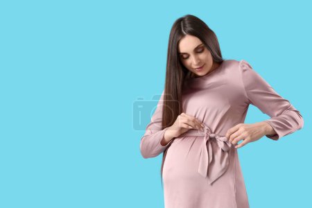 Foto de Mujer embarazada joven en vestido sobre fondo azul - Imagen libre de derechos