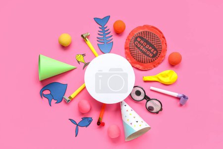 Blanko-Karte mit Papierfischen, Kissen und Party-Dekor auf rosa Hintergrund. Feier zum Aprilscherz