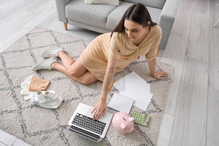 Young pregnant woman using laptop at home. Maternity Benefit concept