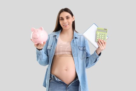 Mujer embarazada joven con alcancía, cuaderno y calculadora sobre fondo claro. Concepto de prestación de maternidad