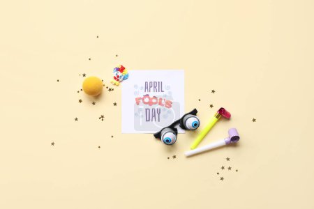 Foto de Postal festiva para el Día de los Inocentes de Abril con gafas divertidas y decoración de fiesta sobre fondo beige - Imagen libre de derechos