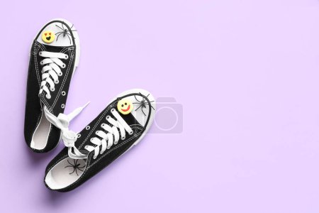 Shoes with tied together laces and fake spiders on lilac background. April Fools Day celebration