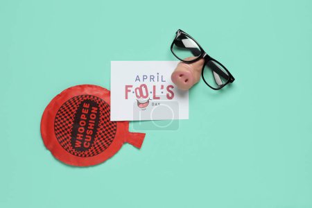 Carte postale festive pour April Fools Day avec des lunettes drôles et un coussin coqueluche sur fond turquoise