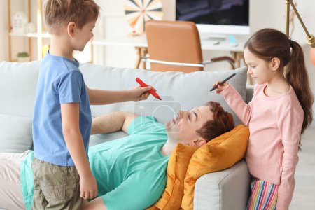 Little children painting face of their sleeping father at home. April Fool's Day prank