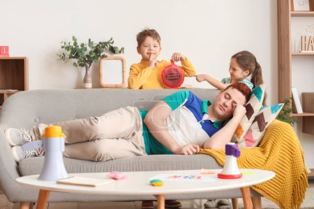 Los niños pequeños planean bromear a su padre dormido con un cojín de whoopee en casa. Broma del Día de los Inocentes