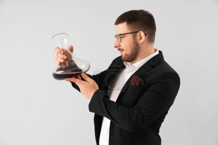 Photo for Young sommelier with decanter of red wine on grey background - Royalty Free Image