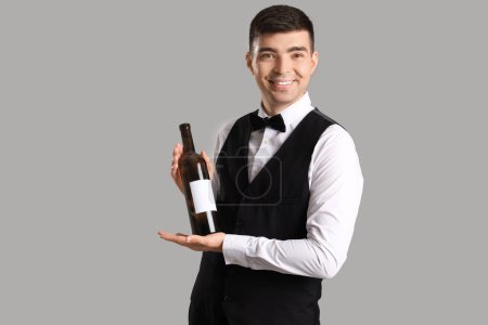 Photo for Young sommelier with bottle of wine on grey background - Royalty Free Image