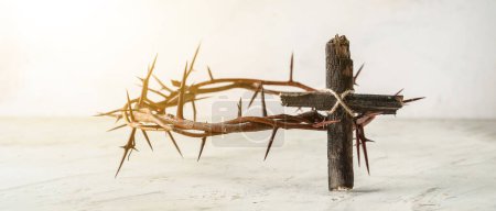 Wooden cross and crown of thorns on light background. Good Friday concept