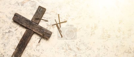 Wooden cross and nails on light grunge background with space for text. Good Friday concept