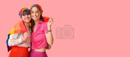 Young lesbian couple with LGBT flag on pink background with space for text
