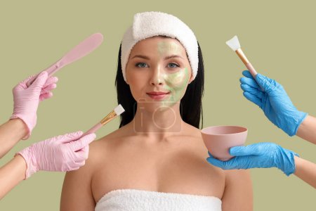 Cosmetologists applying facial mask on young woman's face against green background, closeup