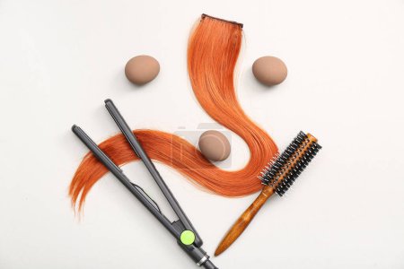 Photo for Hair strand with flattening iron, brush and Easter eggs on white background - Royalty Free Image