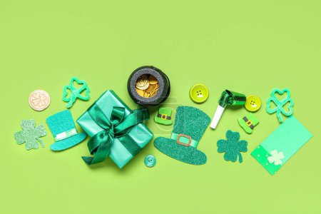 Gift box with pot of coins, party whistle and decor for St. Patrick's Day on green background