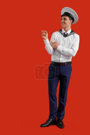 Photo for Young sailor pointing at something on red background - Royalty Free Image