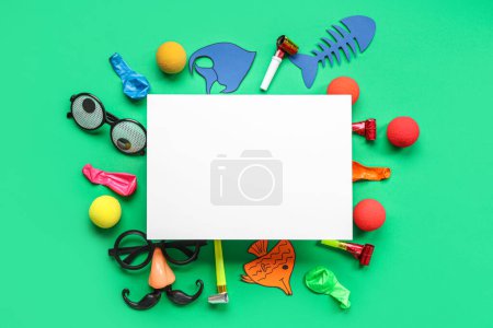 Blank card with paper fishes, funny glasses and party decor on green background. April Fools Day celebration