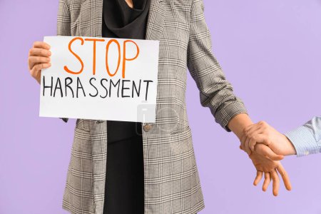 Photo for Business woman holding paper with text STOP HARASSMENT and male colleague grabbing her hand on lilac background, closeup - Royalty Free Image