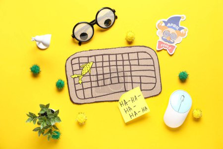 Foto de Teclado de computadora de cartón, nota adhesiva y gafas divertidas sobre fondo amarillo. Broma del Día de los Inocentes - Imagen libre de derechos