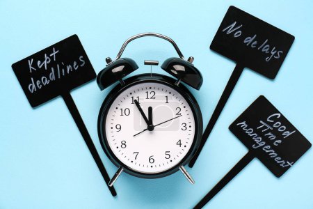 Motivation phrases with alarm clock on blue background. Time management. Top view