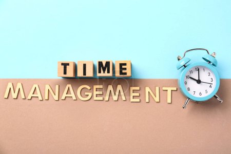Text TIME MANAGEMENT with alarm clock on blue and brown background. Top view