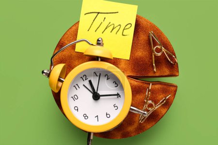 Text TIME with alarm clock and paper clips on green background. Time management. Top view