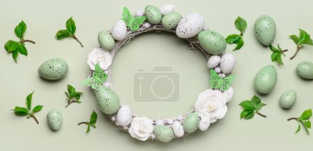 Photo for Easter wreath, eggs and leaves on green background, top view - Royalty Free Image