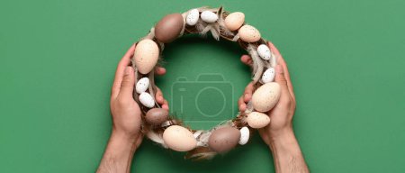 Photo for Male hands holding Easter wreath on green background, top view - Royalty Free Image