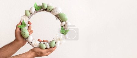 Photo for Male hands holding Easter wreath on white background with space for text - Royalty Free Image