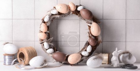 Photo for Easter wreath made of eggs and feathers on table near light wall - Royalty Free Image