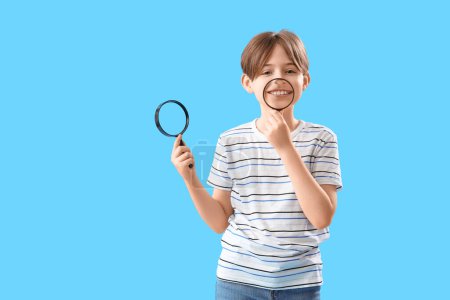 Little boy with magnifiers on blue background