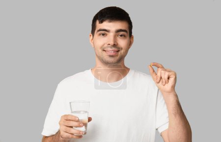 Photo for Young man with vitamin A pill and glass of water on light background - Royalty Free Image