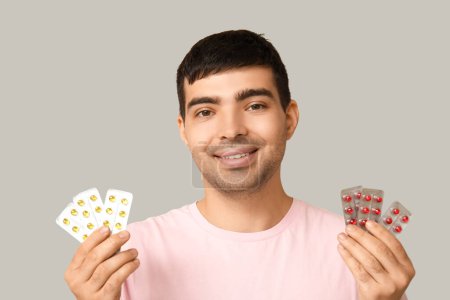 Foto de Hombre joven con ampollas de píldoras de vitamina A sobre fondo claro, primer plano - Imagen libre de derechos