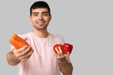 Junger Mann mit vitaminreichem Gemüse auf hellem Hintergrund