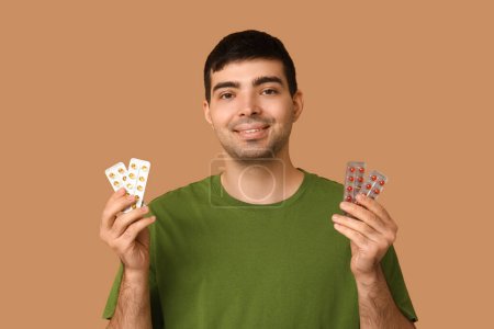 Foto de Hombre joven con ampollas de píldoras de vitamina A sobre fondo beige - Imagen libre de derechos