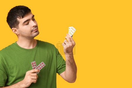 Foto de Hombre joven con ampollas de píldoras de vitamina A sobre fondo amarillo, primer plano - Imagen libre de derechos