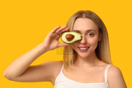 Photo for Young woman with avocado on yellow background, closeup - Royalty Free Image