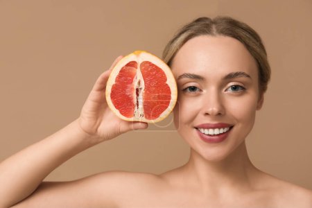 Photo for Young woman with grapefruit on beige background, closeup - Royalty Free Image