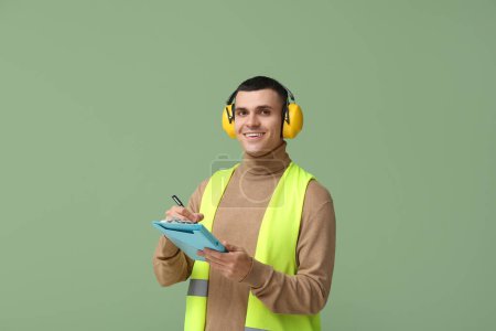 Foto de Joven ingeniero masculino con portapapeles sobre fondo verde - Imagen libre de derechos
