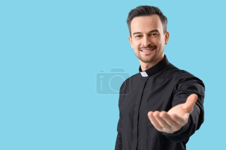 Porträt eines männlichen Priesters, der auf blauem Hintergrund die Hand ausstreckt