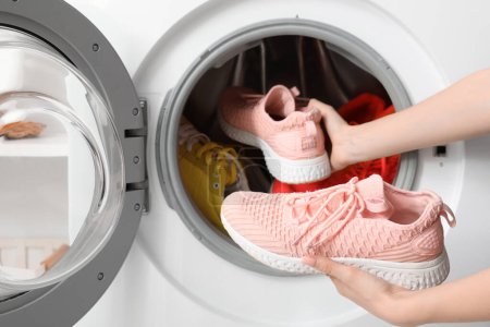 Frau steckt Turnschuhe in Waschmaschine, Nahaufnahme