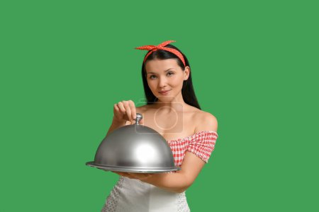 Téléchargez les photos : Belle jeune serveuse avec plateau et cloche sur fond vert - en image libre de droit