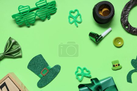 Frame made of eyeglasses with gift box, party whistle and decor for St. Patrick's Day on green background