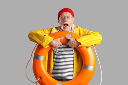 Photo for Shocked mature sailor with ring buoy on grey background - Royalty Free Image