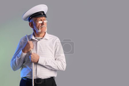Photo for Mature sailor with rope on grey background - Royalty Free Image