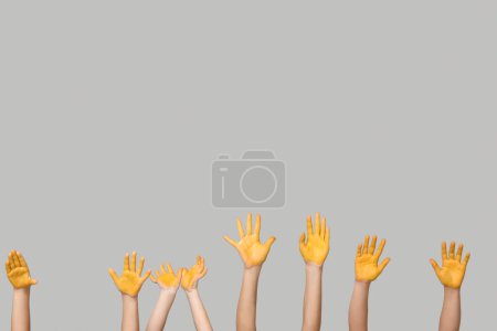 Téléchargez les photos : Mains d'enfants avec peinture jaune sur fond gris. Journée internationale du cancer chez les enfants - en image libre de droit