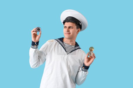 Thoughtful young sailor with compasses on blue background
