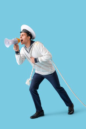 Young sailor with rope shouting into megaphone on blue background