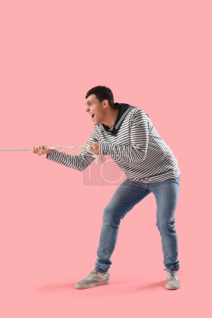 Jeune marin en colère tirant la corde sur fond rose