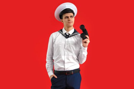 Photo for Young sailor with binoculars on red background - Royalty Free Image