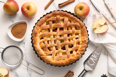 Tasty homemade apple pie with fruits, cinnamon and spatula on white grunge background